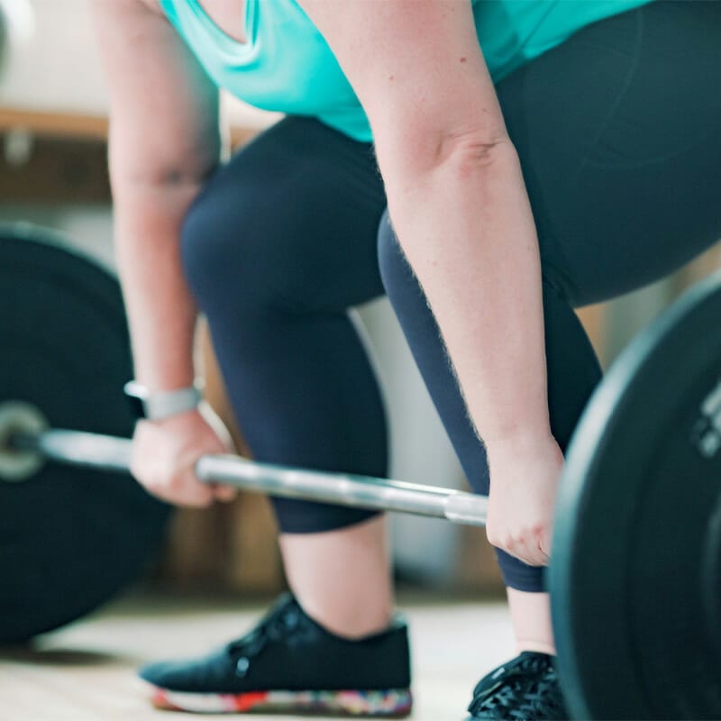 Woman pulling weights at Hybrid Fitness Academy